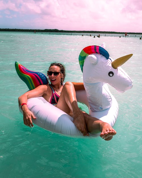 Happy Woman Swimming in Inflatable Unicorn