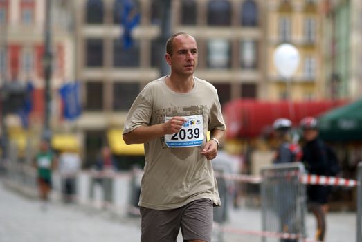 Focused male runner participating in the Wrocław marathon on city streets.