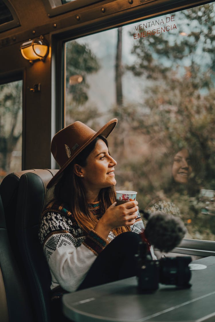 Woman Sitting In A Train By The Window And Holding A Cup 