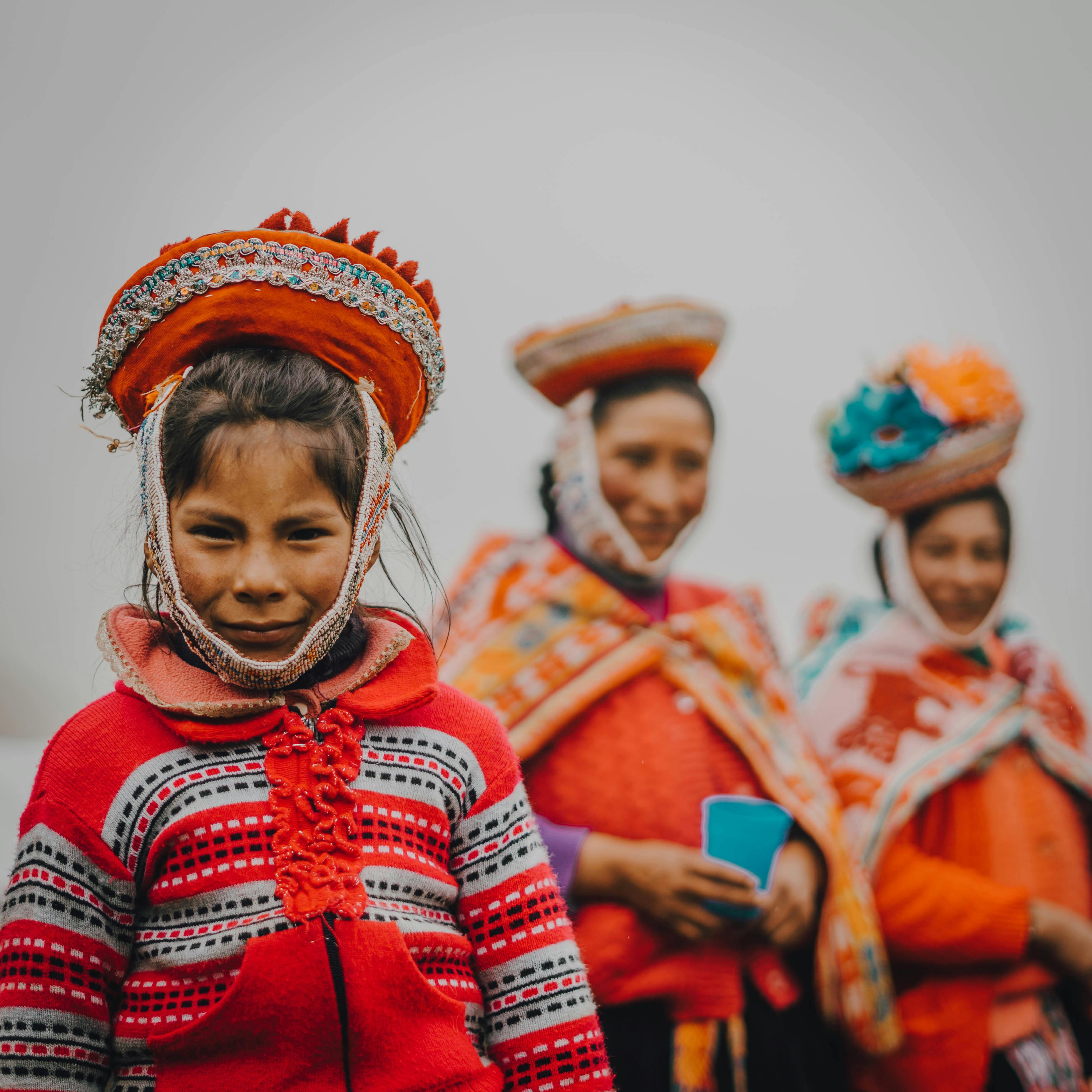 Portrait of women and girl in vibrant traditional Andean clothing, showcasing cultural heritage.