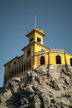 Yellow Castillo Forga perched on rocky cliffs in Mollendo, Peru, an iconic landmark.