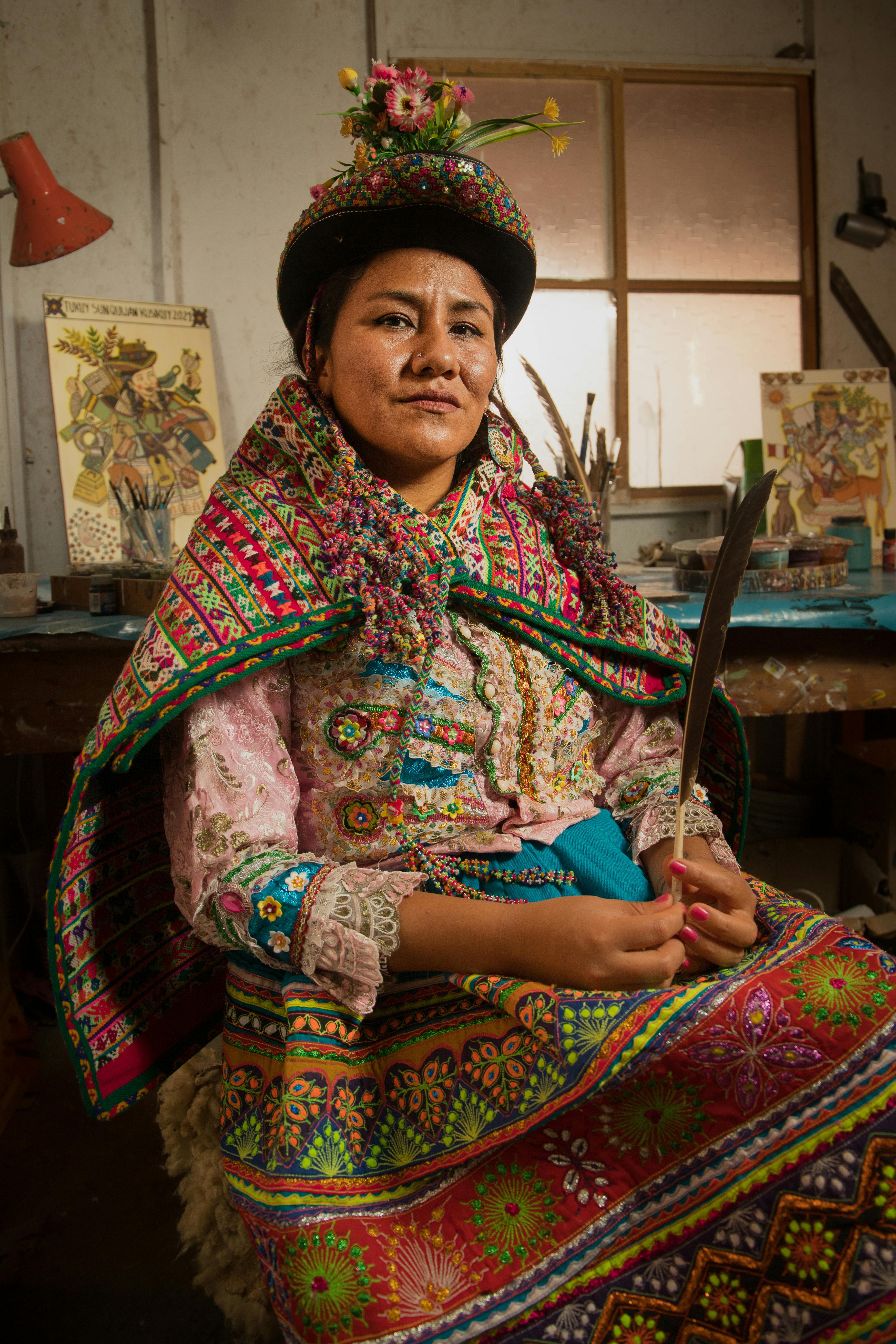 Woman in vibrant traditional Peruvian clothing seated in a Chorrillos workshop, Perú.