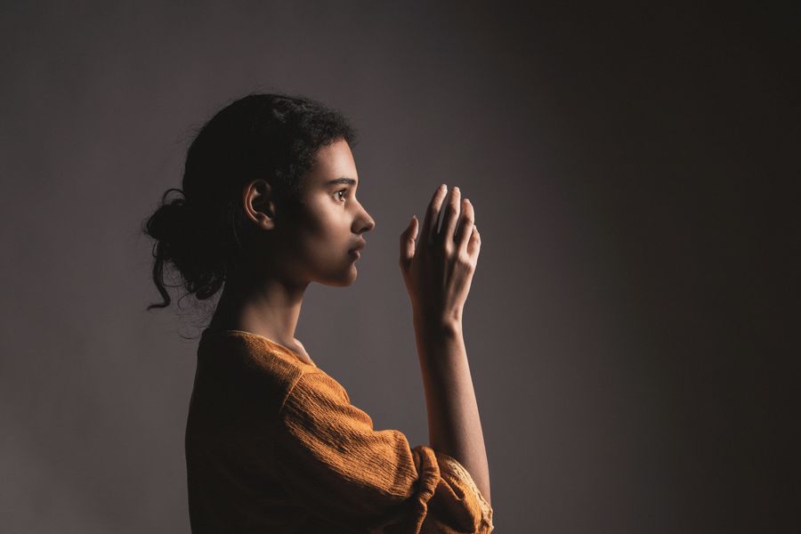 A woman in side light with her hand raised near her face