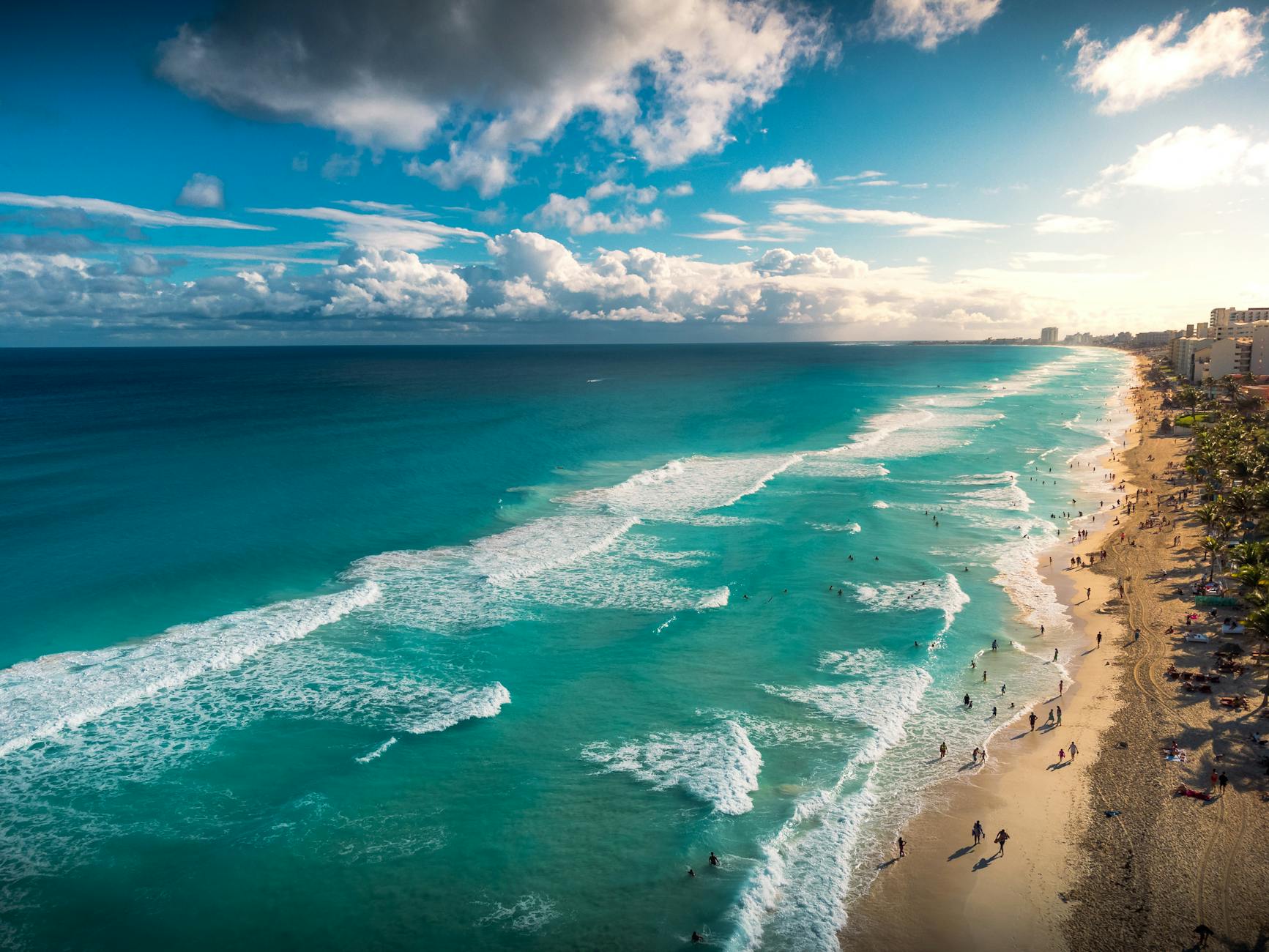 Stunning aerial view of Cancún's beach with turquoise waves and clear sky, capturing the tropical paradise's vibrant essence.