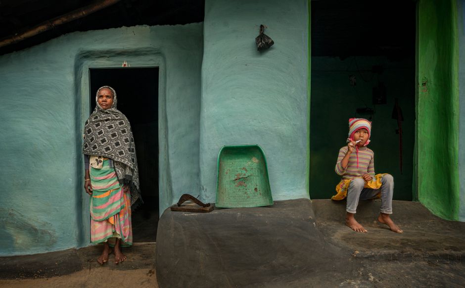 A woman and a child outside a clay house in Jhargram, India, showcasing rural life