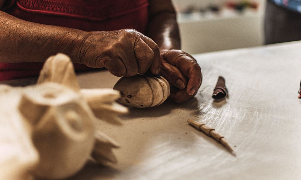 Close-up of an artisan's hands carving wood, representing turning a Destiny Matrix talent into a skilled profession