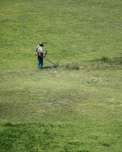 High Angle Shot of Man on a Field with a Grass Trimmer 