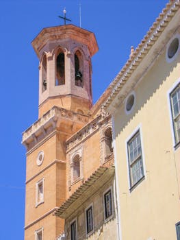 Sunlit view of a historic church tower in Ciudadela de Menorca, showcasing religious architecture.