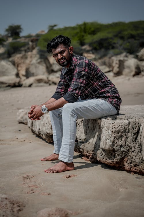 Man in Shirt Sitting on Rock