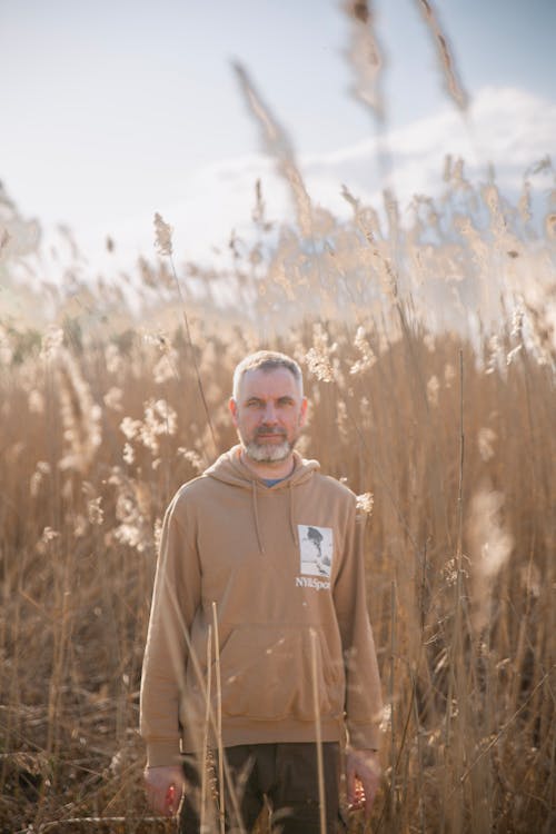 Man with Gray Hair and Beard Standing among Dry, High Grass 
