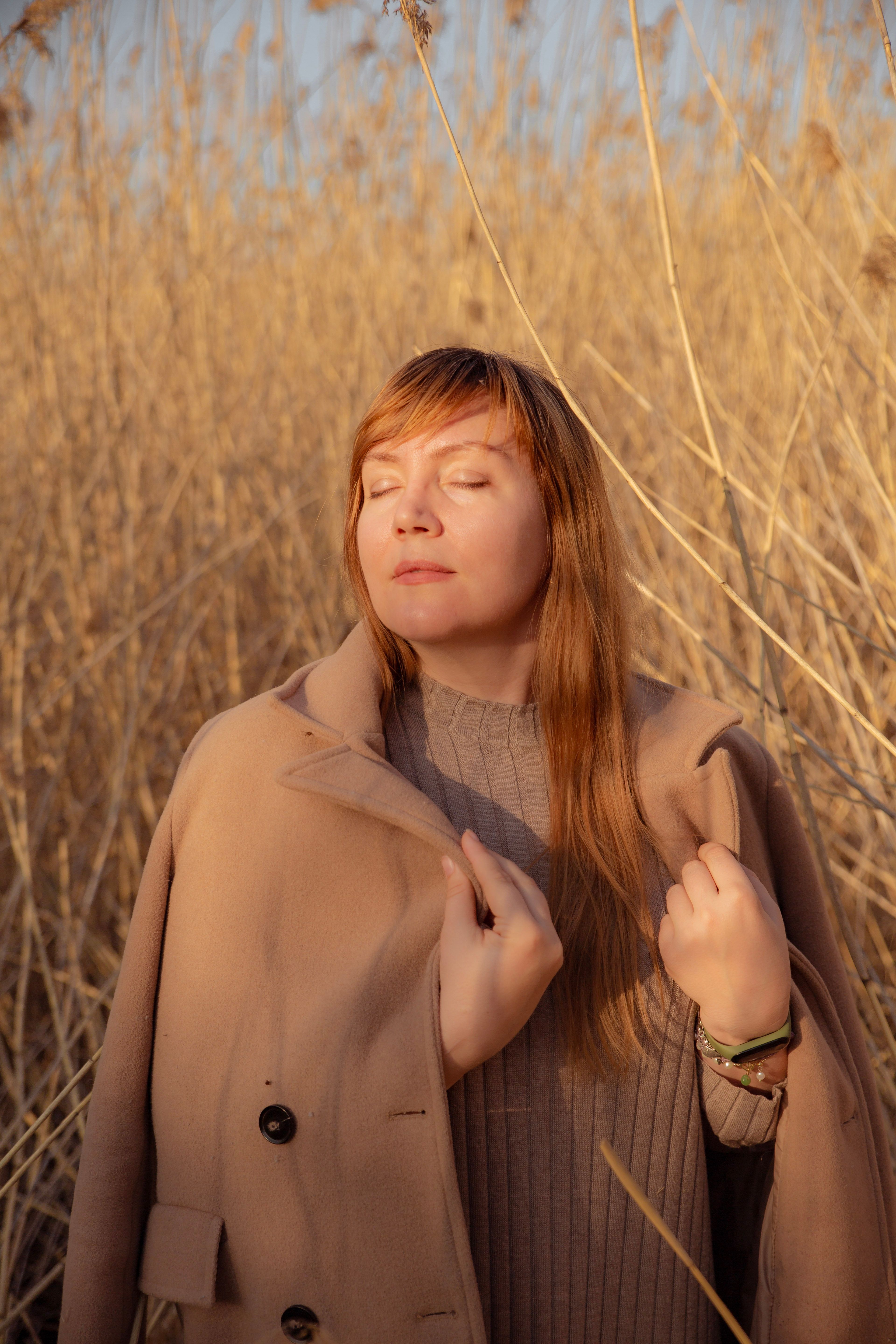 Woman in a Beige Coat Among Dry Tall Grass · Free Stock Photo