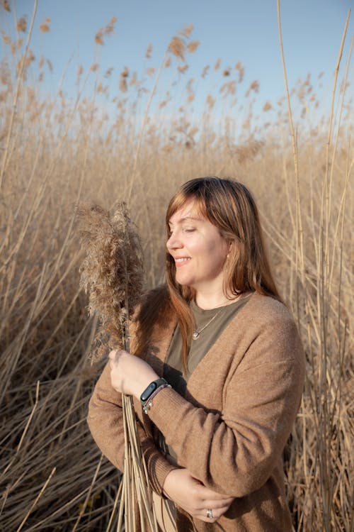 Woman in a Brown Cardigan Among Tall Dry Rushes