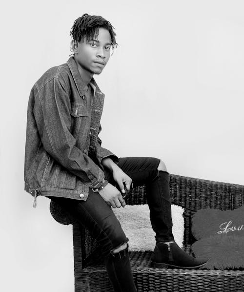 Black and White Photo of a Young Man in a Jean Jacket and Ripped Jeans 