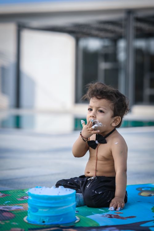 Free Cute toddler with cake on face during outdoor birthday celebration near pool. Stock Photo