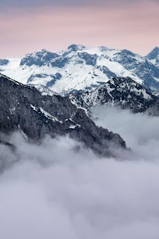 Majestic snow-covered mountains over foggy valleys in Berchtesgaden, Germany, at twilight.