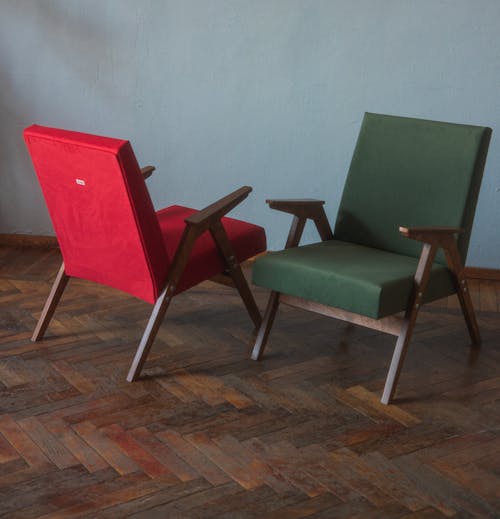 Red and Green Vintage Armchairs Standing on a Wooden Floor 