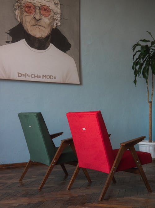 Red and Green Vintage Armchairs Standing on a Wooden Floor 