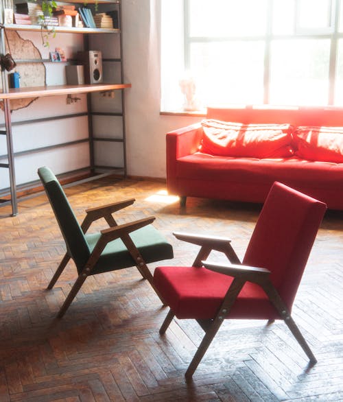 Green and Red Vintage Armchairs Standing on a Wooden Floor 