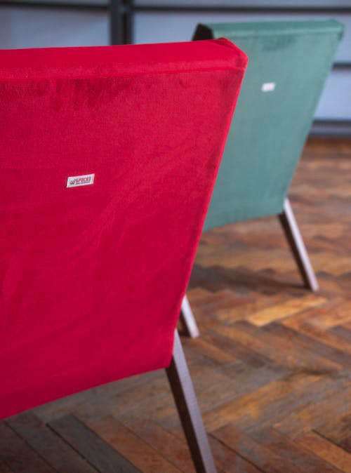 Red and Green Vintage Armchairs Standing on a Wooden Floor 