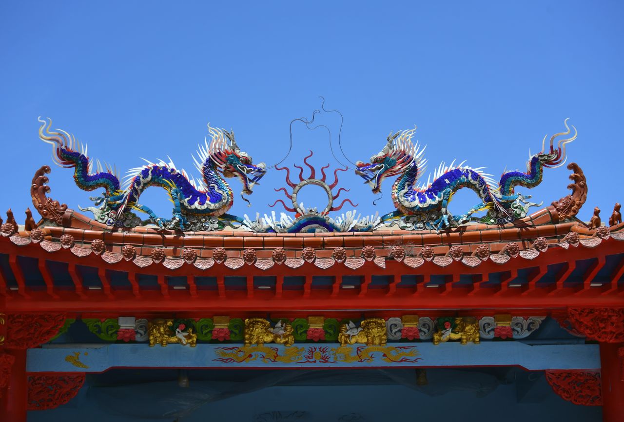 vibrant dragon sculptures adorn a traditional temple roof under a clea