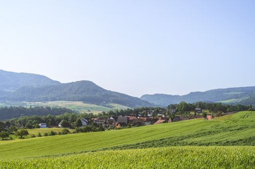 Free A peaceful rural scene with lush fields and a picturesque village nestled in rolling hills. Stock Photo
