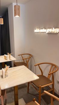 Warm cafe scene with wooden chairs, tables, and a glowing wall sign.