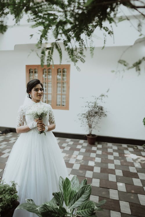 Bride Standing in a Room with a Bouquet of Flowers in her Hands 