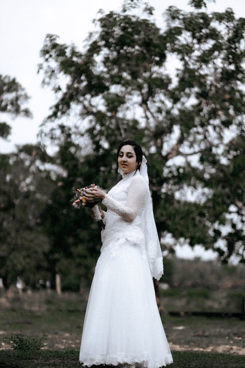 Bride Standing with a Bouquet of Flowers in her Hands 