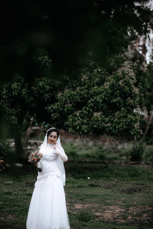 Bride in Wedding Dress Posing near Tree
