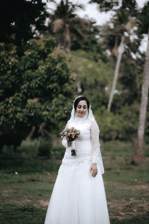 Bride Standing and Holding a Bouquet of Flowers 