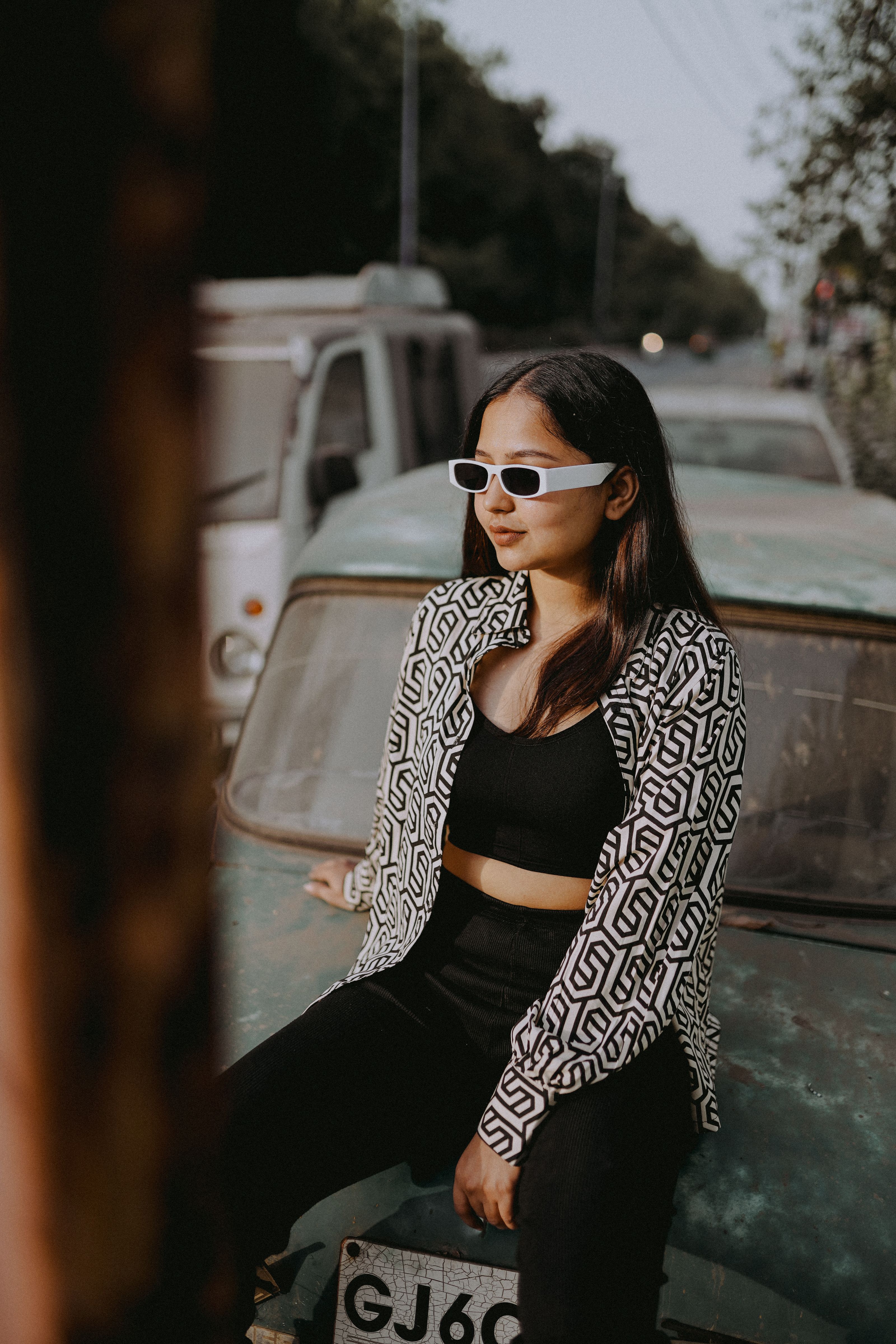 Uma jovem fashionista em um traje chique senta-se confiante em um carro vintage, exalando estilo retrô.