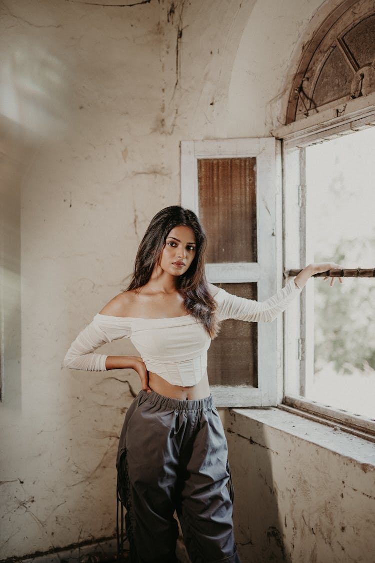 Young Brunette Standing By The Window In An Abandoned House 