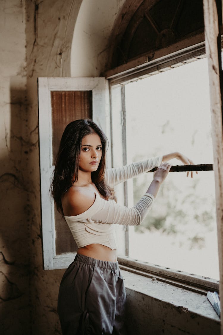 Young Brunette Standing By The Window In An Abandoned House 