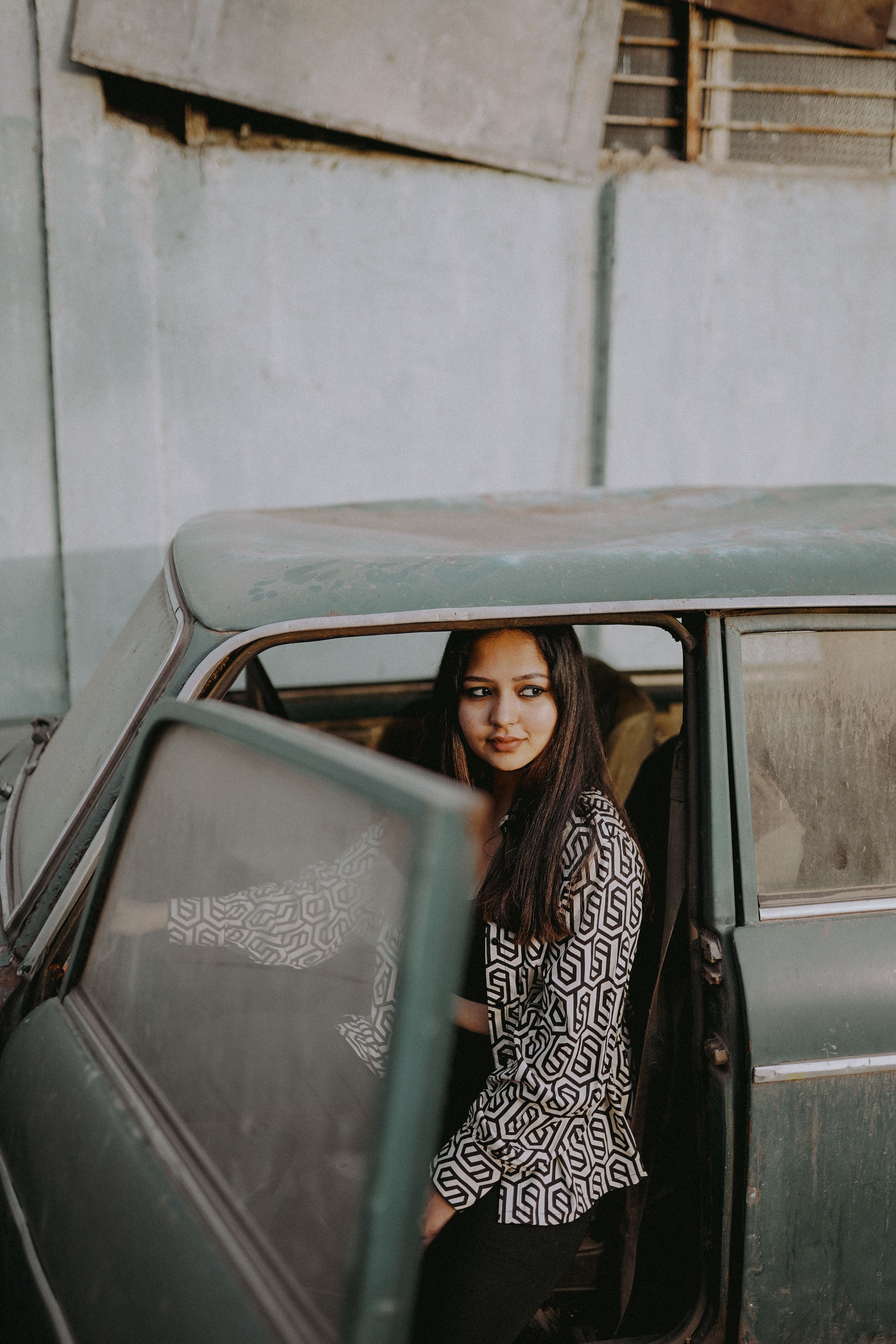 Young woman in retro outfit seated in an old car, capturing a trendy vintage vibe.