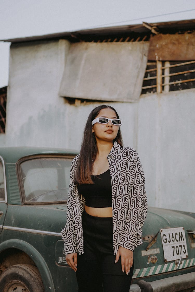 Young Woman Standing By An Old Car