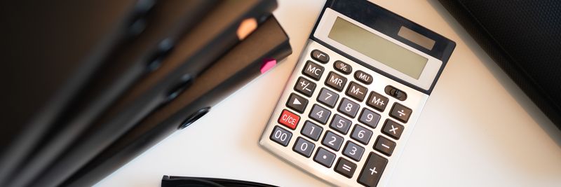 Calculator with glasses and folders on an office desk. Perfect for finance and accounting themes.