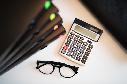 Calculator with glasses and folders on an office desk. Perfect for finance and accounting themes.