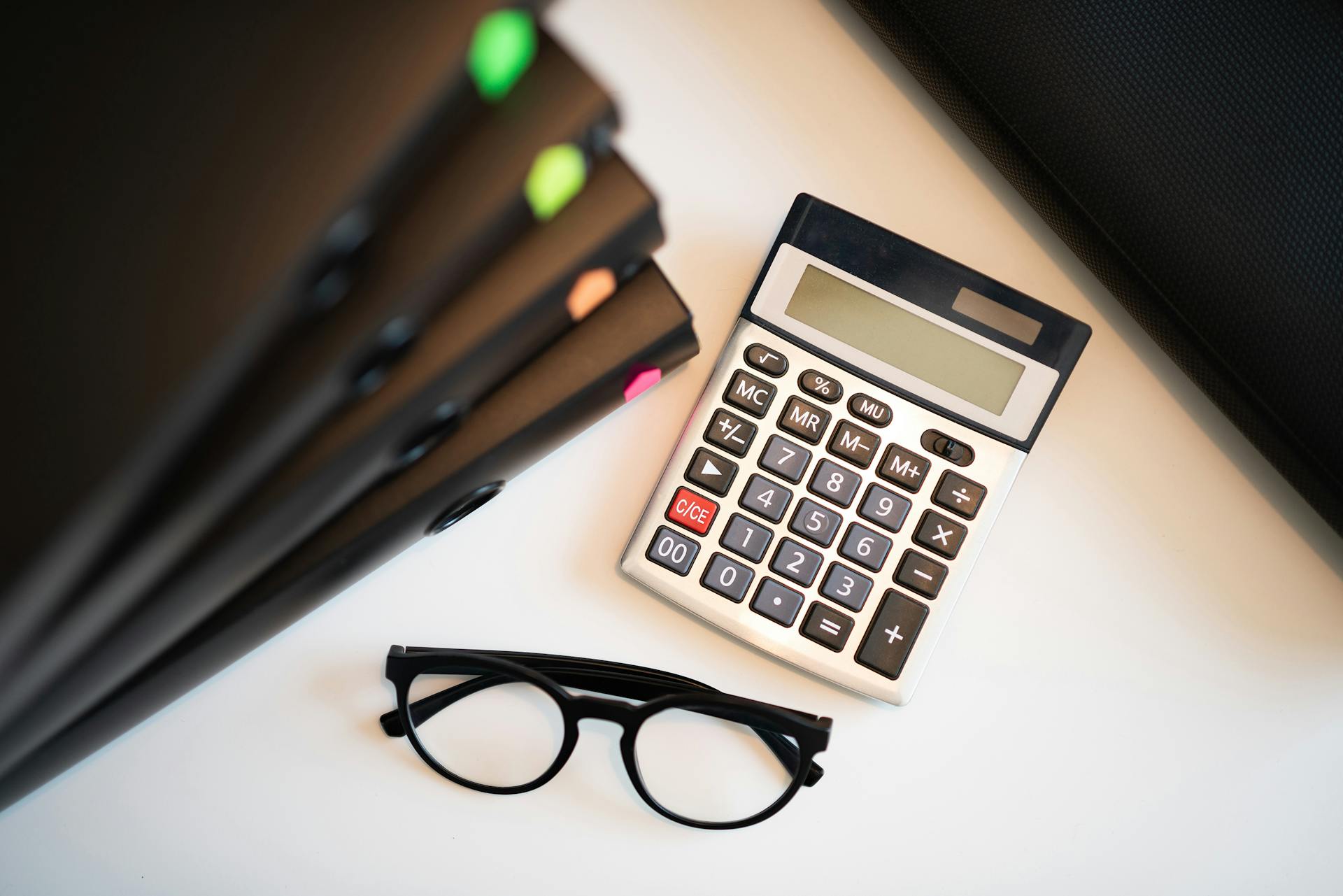 Calculator with glasses and folders on an office desk. Perfect for finance and accounting themes.