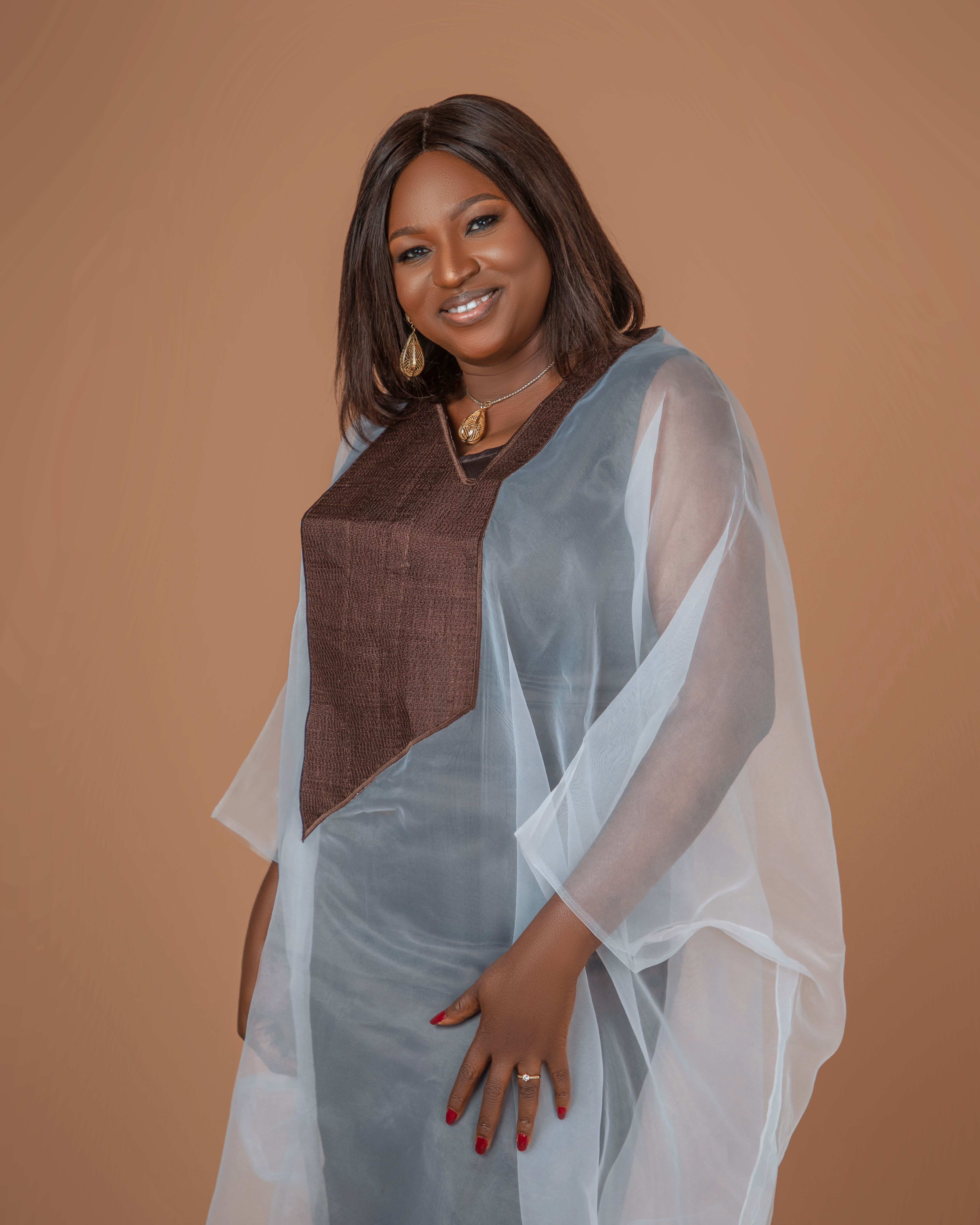 Chic portrait of a smiling woman in elegant layers with a brown background.