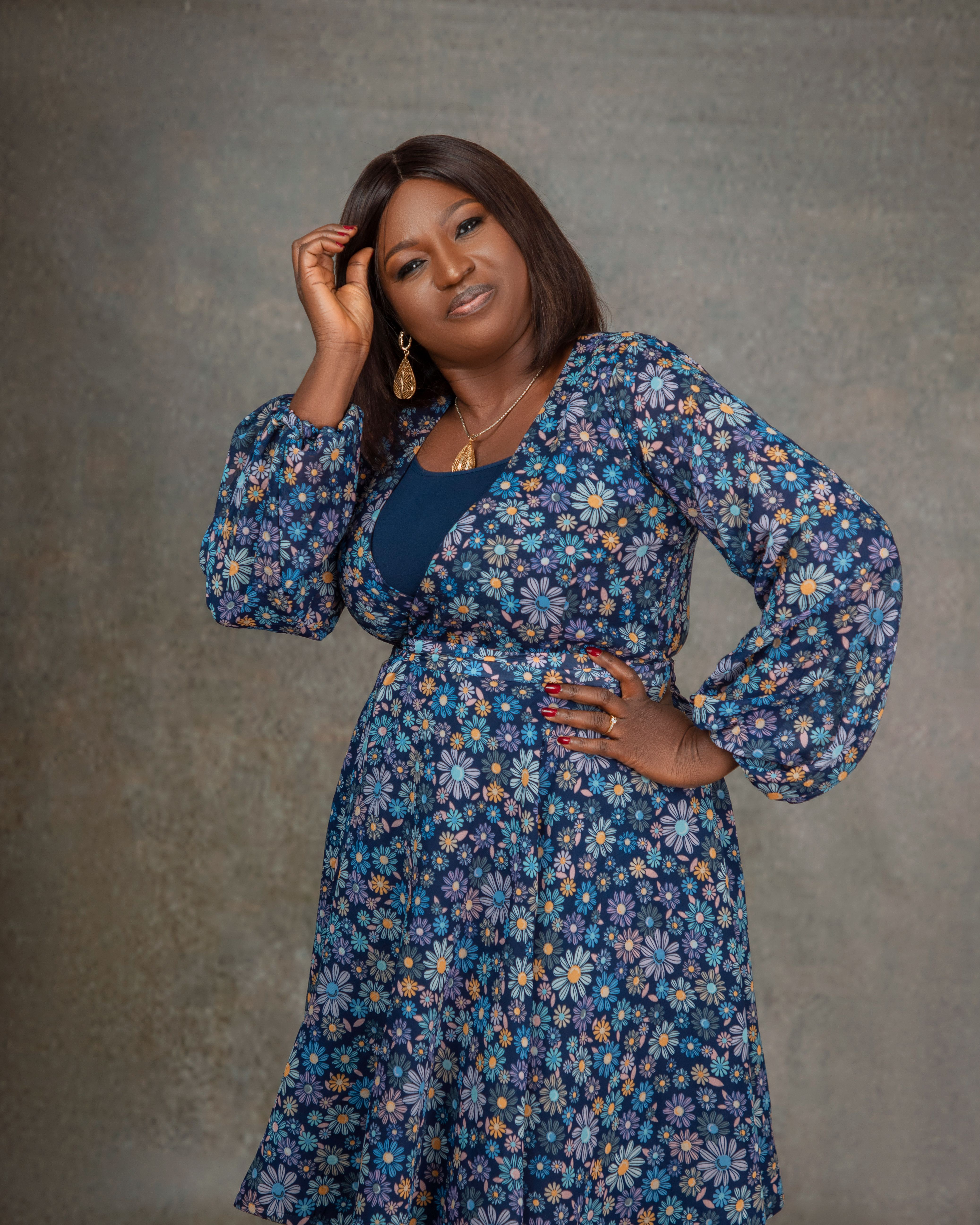 Stylish woman with floral dress poses confidently in studio setting, showcasing modern fashion.
