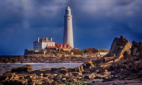 Free Lighthouse on rocks with dramatic clouds in Northumberland, UK coast. Stock Photo