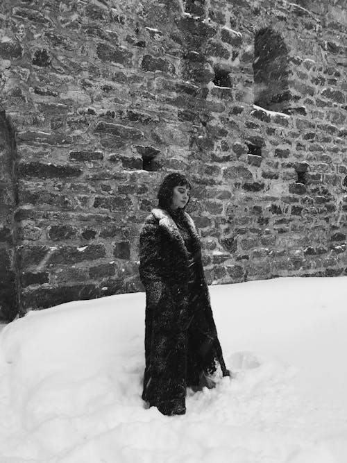 Woman in Coat Posing by Castle Wall in Winter