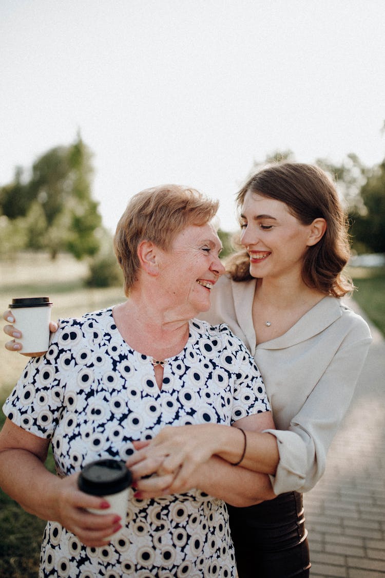 Mother And Daughter Standing Close To Each Other And Smiling 