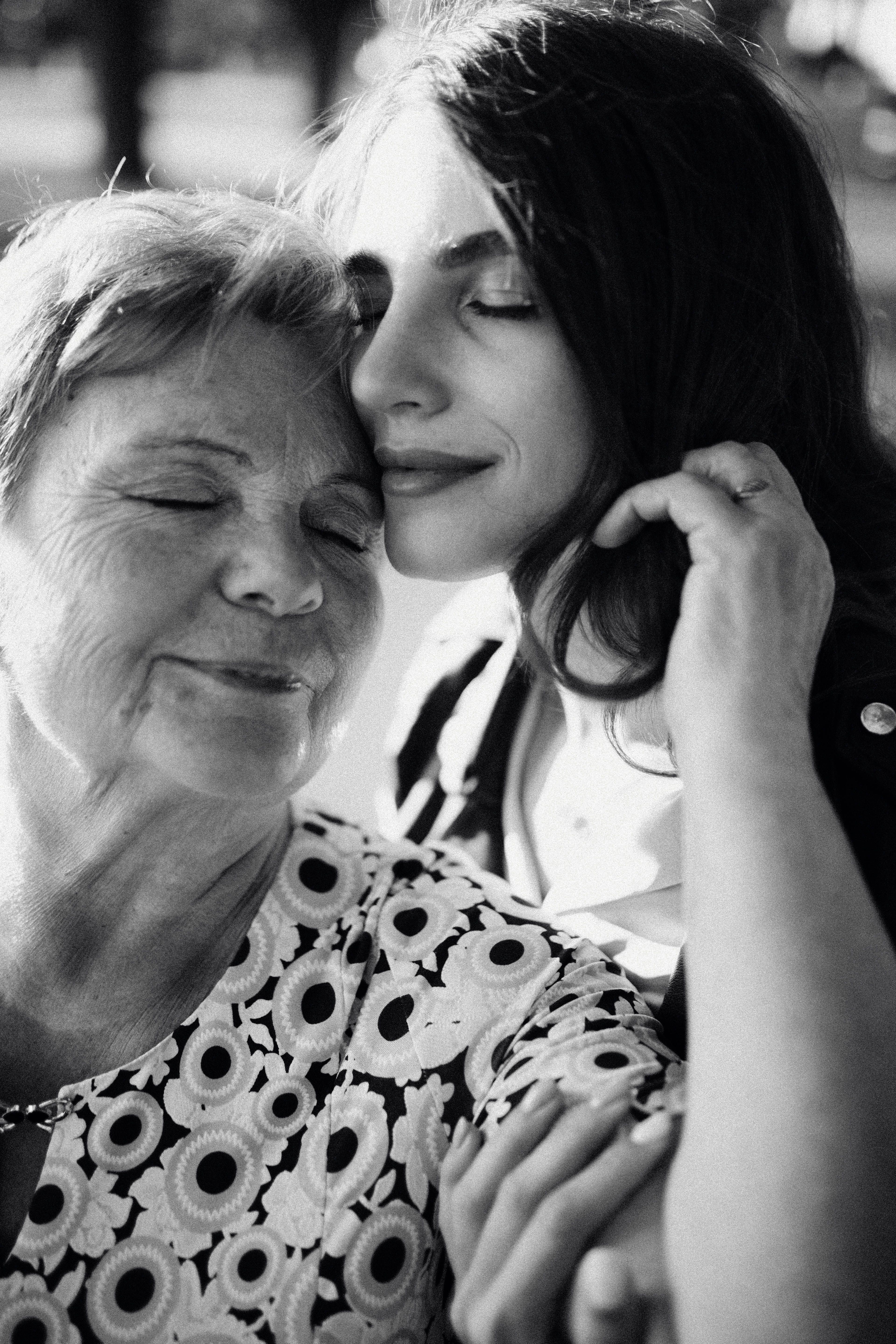Heartwarming black and white portrait of a mother and daughter embracing with eyes closed.