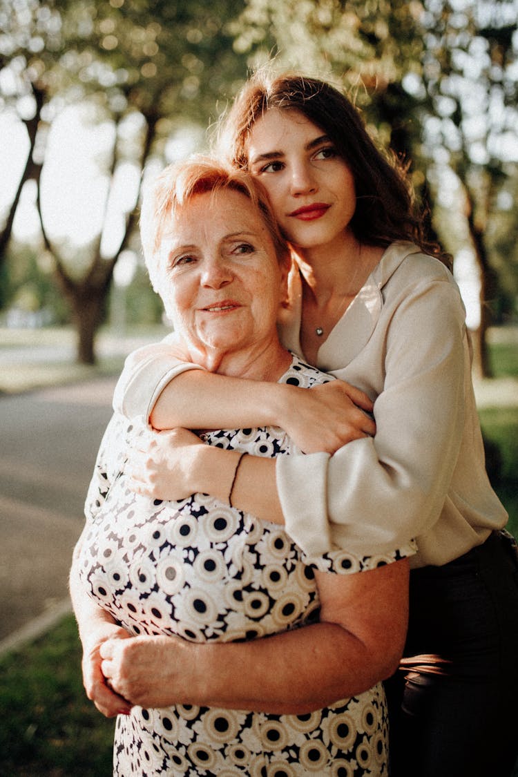 Mother And Daughter Hugging While Standing In A Park 