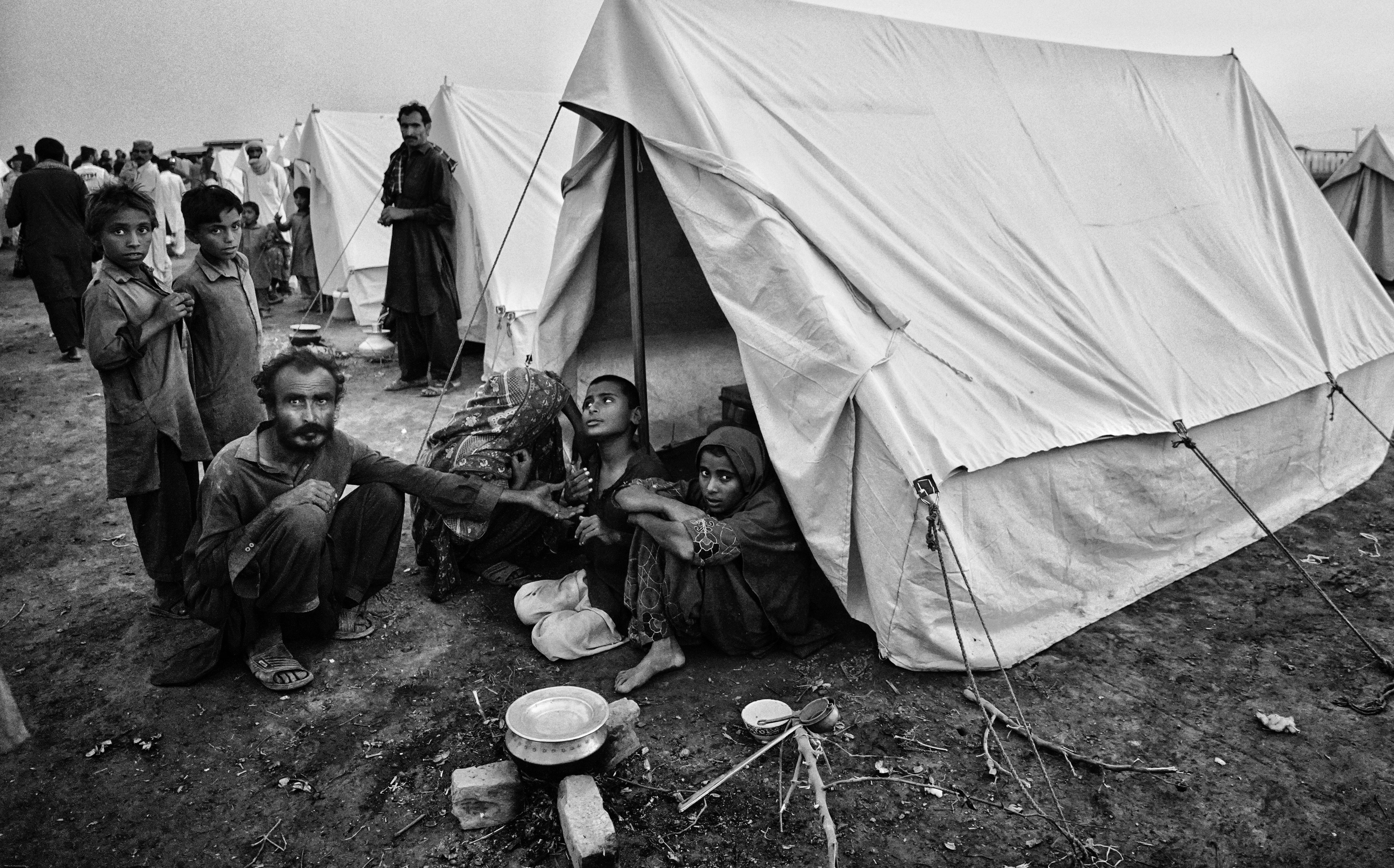 Des familles rassemblées dans un camp de réfugiés vivant sous des tentes.