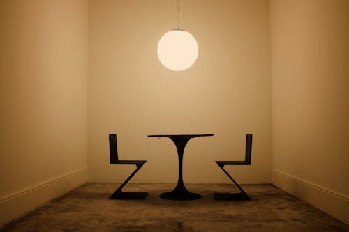 Modern Table with Two Chairs Standing under a Hanging Light 