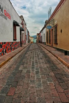 Explore a charming cobblestone street surrounded by colorful buildings in a quaint town on an overcast day.