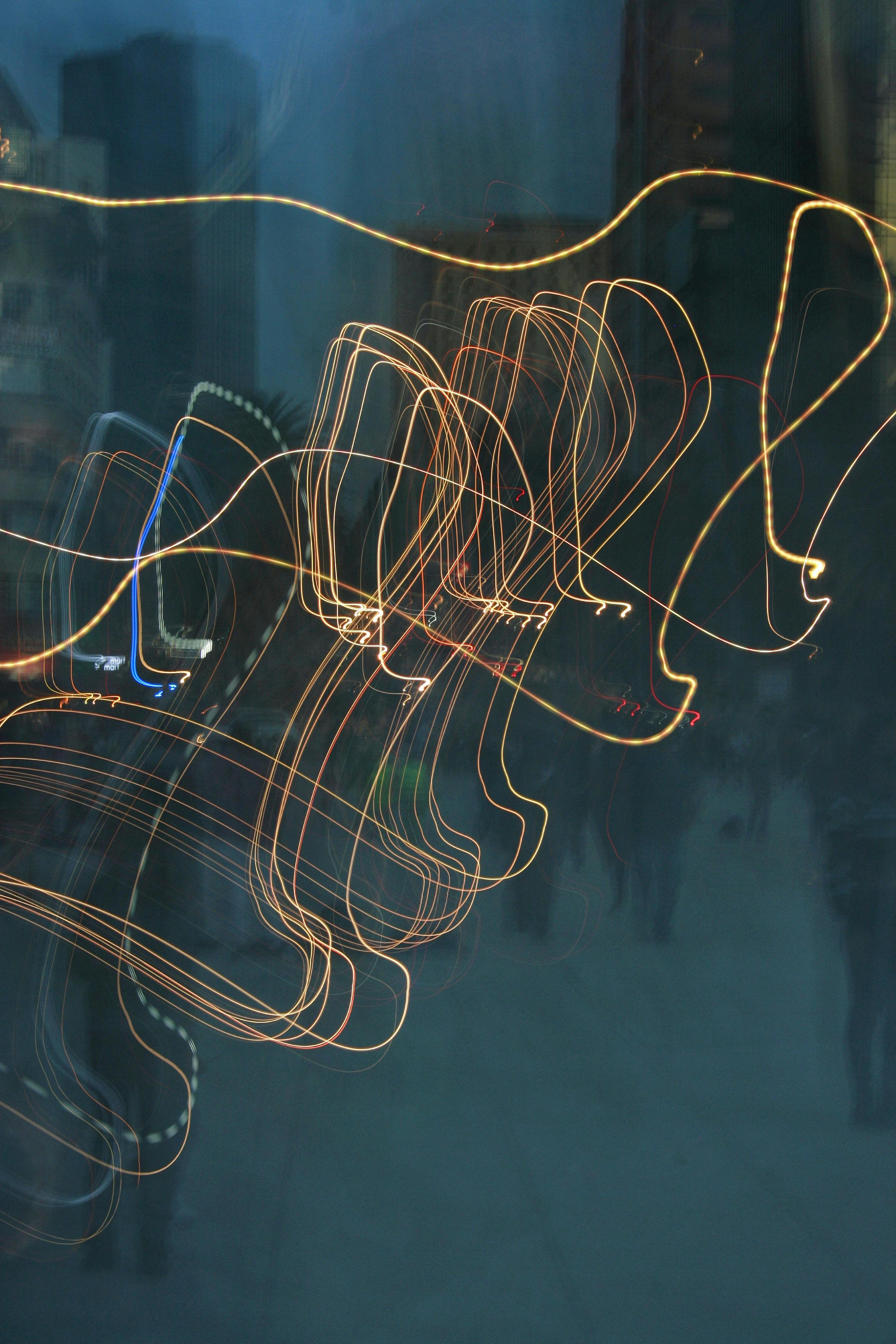 Vibrant abstract light trails create dynamic patterns in an urban nighttime setting.