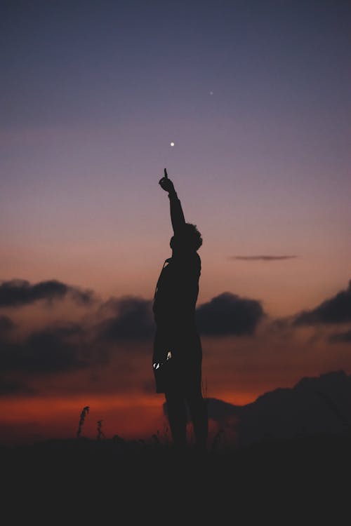 Man Standing with Arm Raised at Sunset